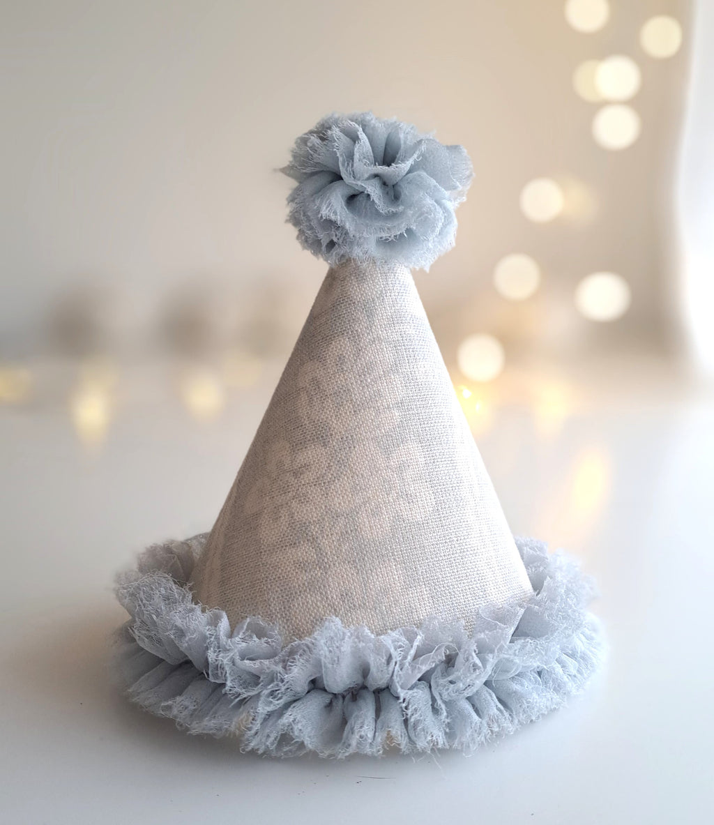 Party hat with lace trim and floral top against a soft, blurred background.