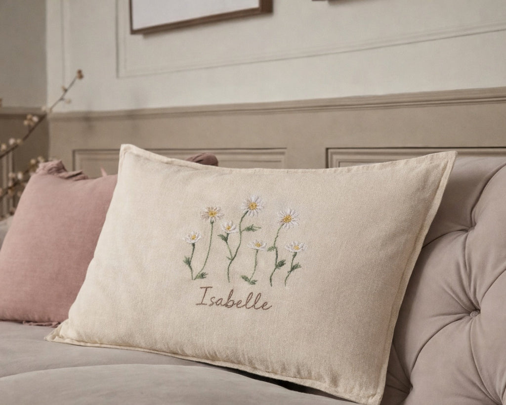 Decorative pillow with floral embroidery and text on a bed- personalised baby / toddler gift.