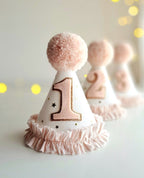 Pink and white birthday hat with number 1 on a light background.