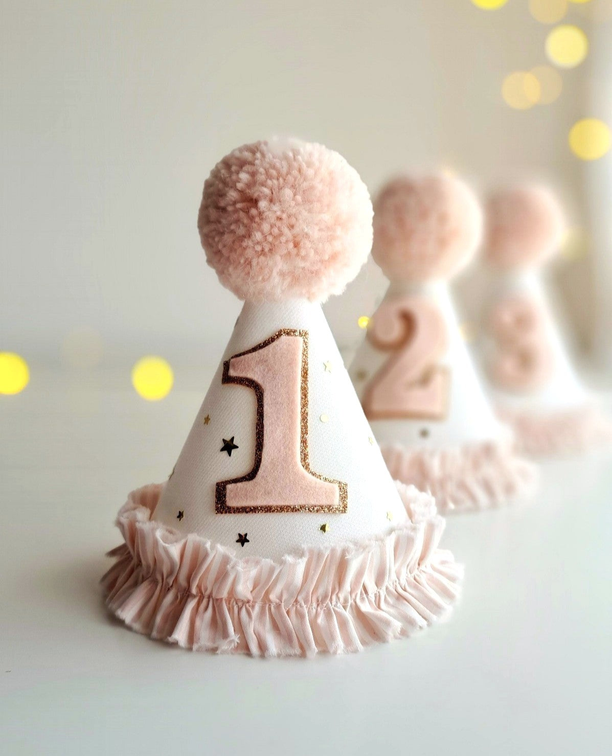 Pink and white birthday hat with number 1 on a light background.