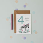 Birthday card with a zebra illustration and 'Four Today' text, placed on a light blue background with colourful dots.