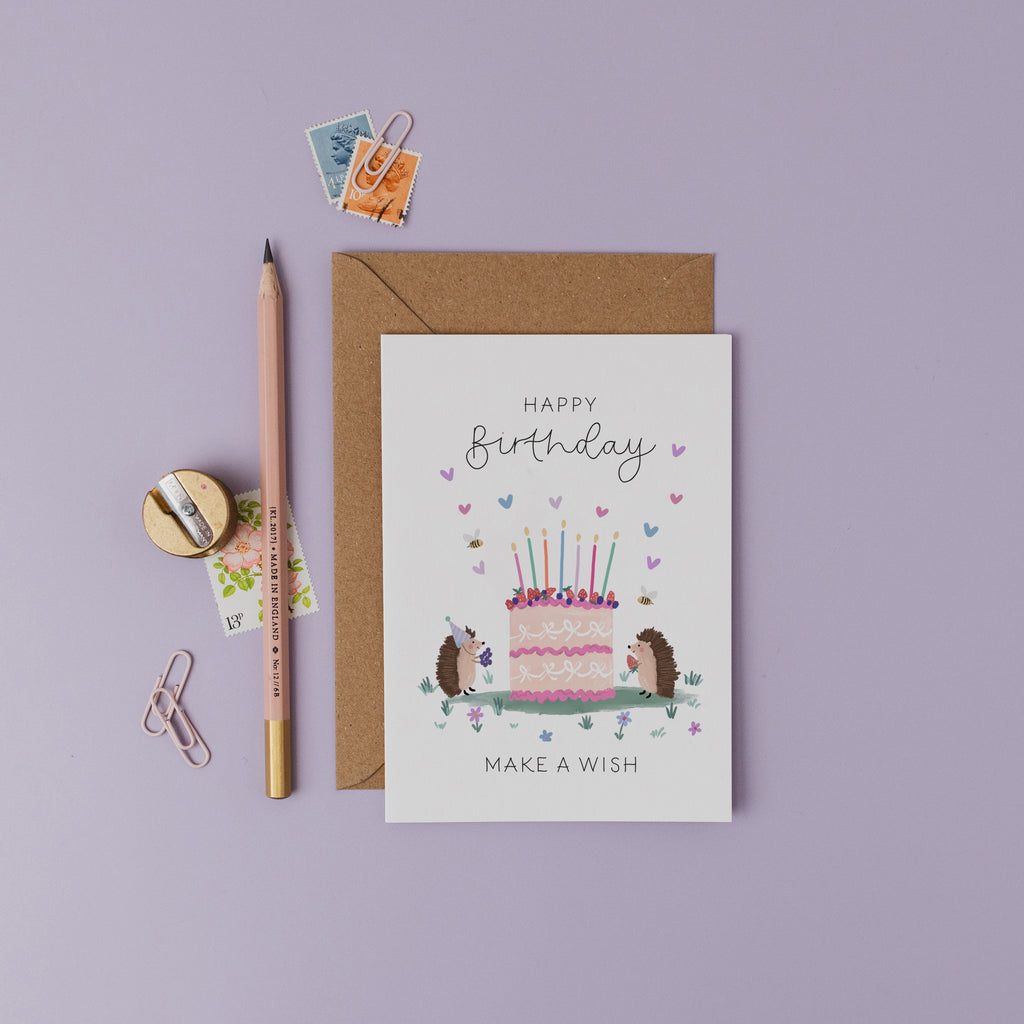 Birthday card with hedgehogs and cake illustration on a purple background.
