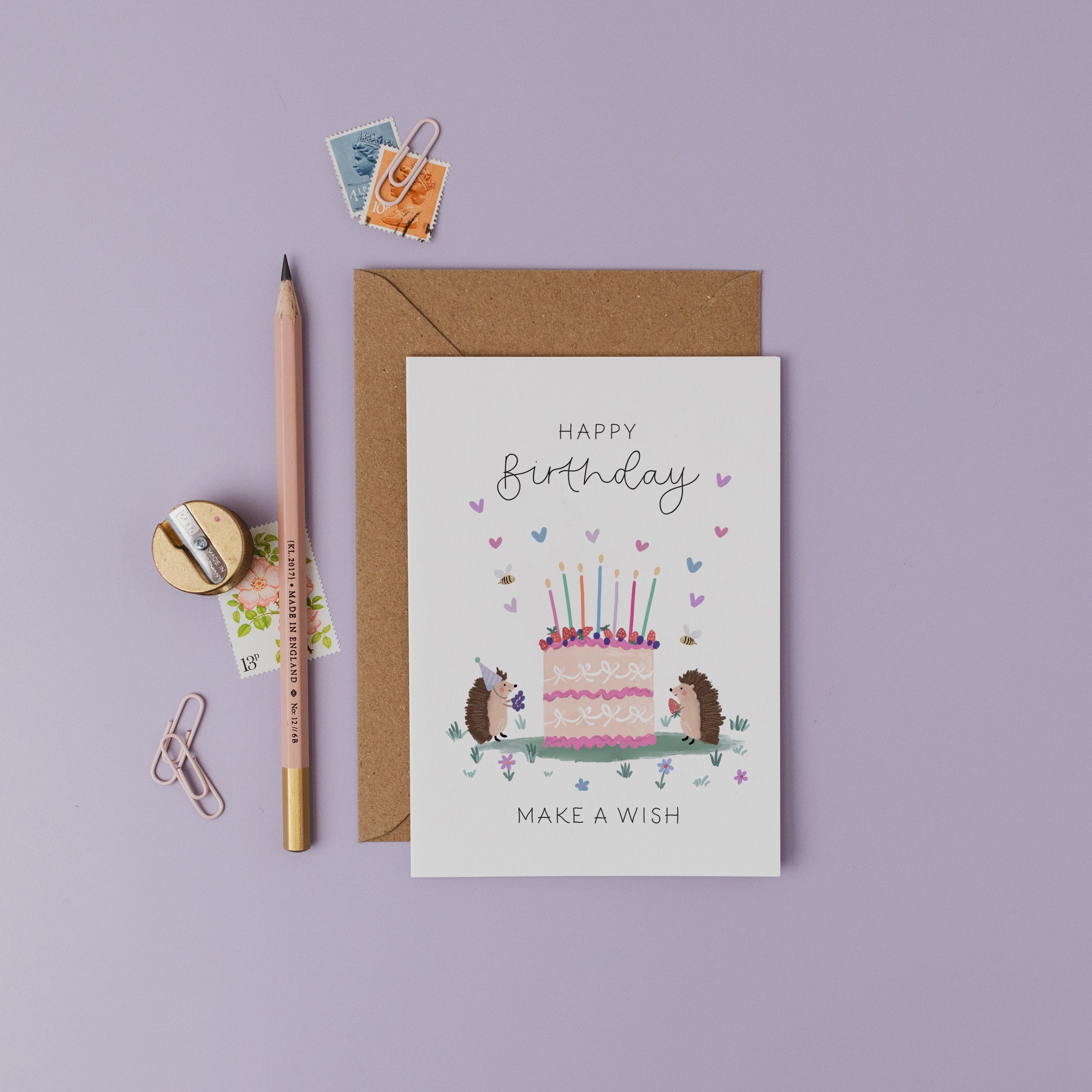 Birthday card with hedgehogs and cake illustration on a purple background.