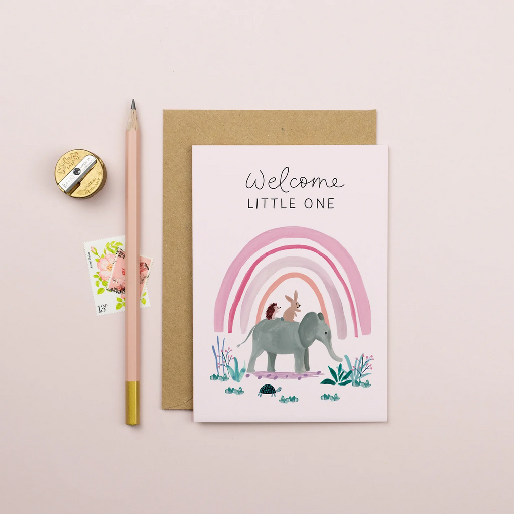 Greeting card with elephant and rainbow illustration on a beige background.