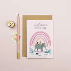 Greeting card with elephant and rainbow illustration on a beige background.