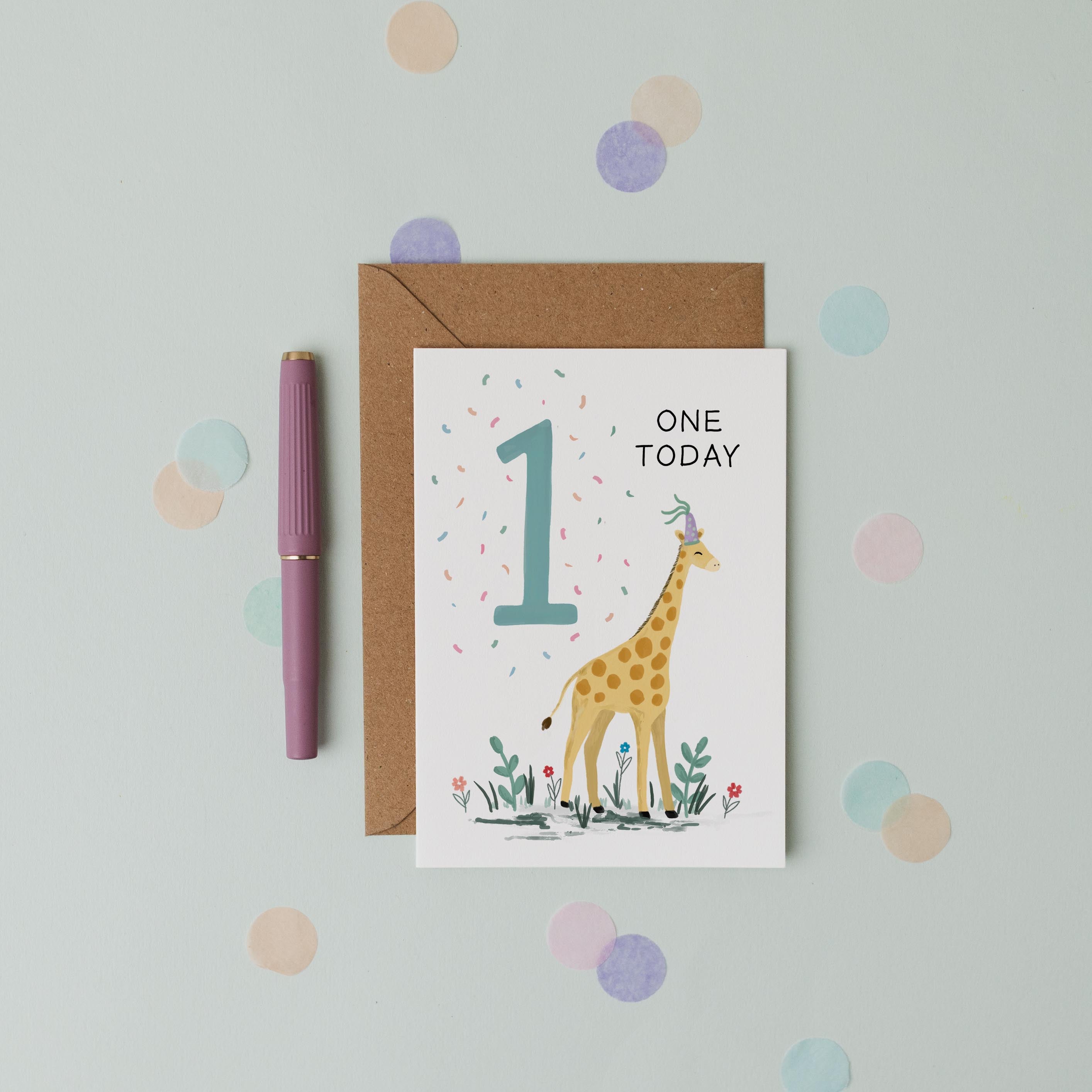 Greeting card with a giraffe illustration and 'One Today' text, placed on a light blue background with polka dots.