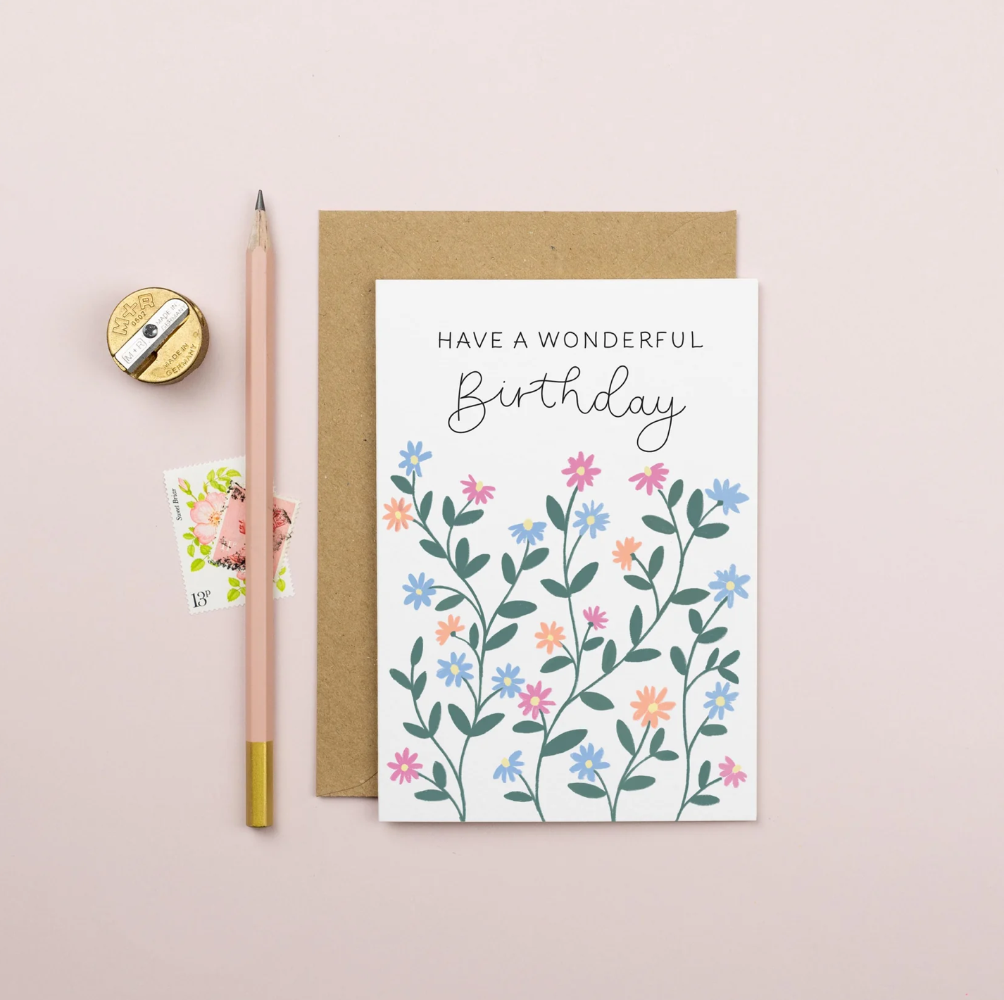 Birthday card with floral design and text 'Have a wonderful birthday' on a pink background with a pencil and sharpener.