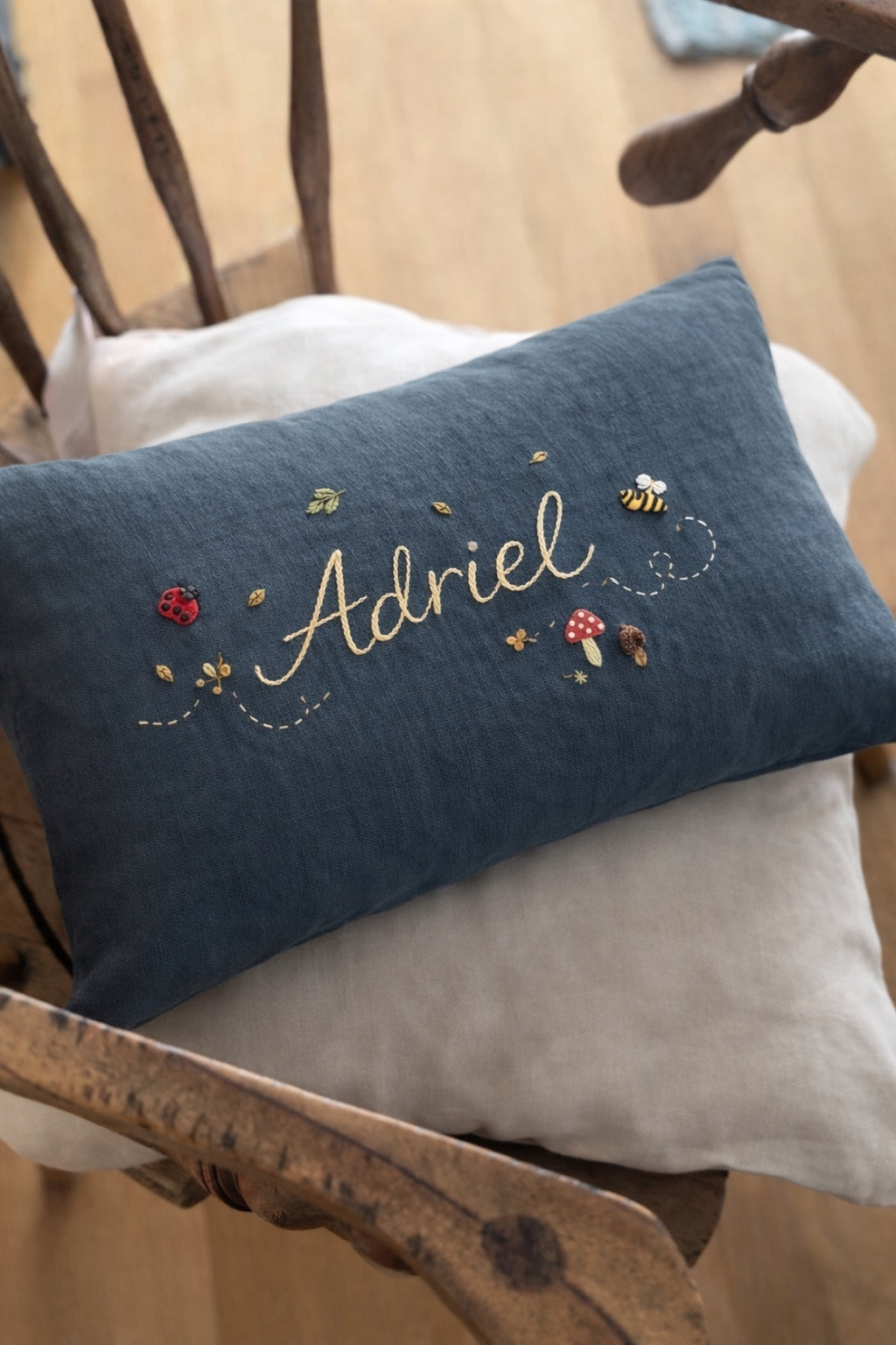 Blue embroidered pillow with name on a wooden chair -  personalised baby / toddler gift.