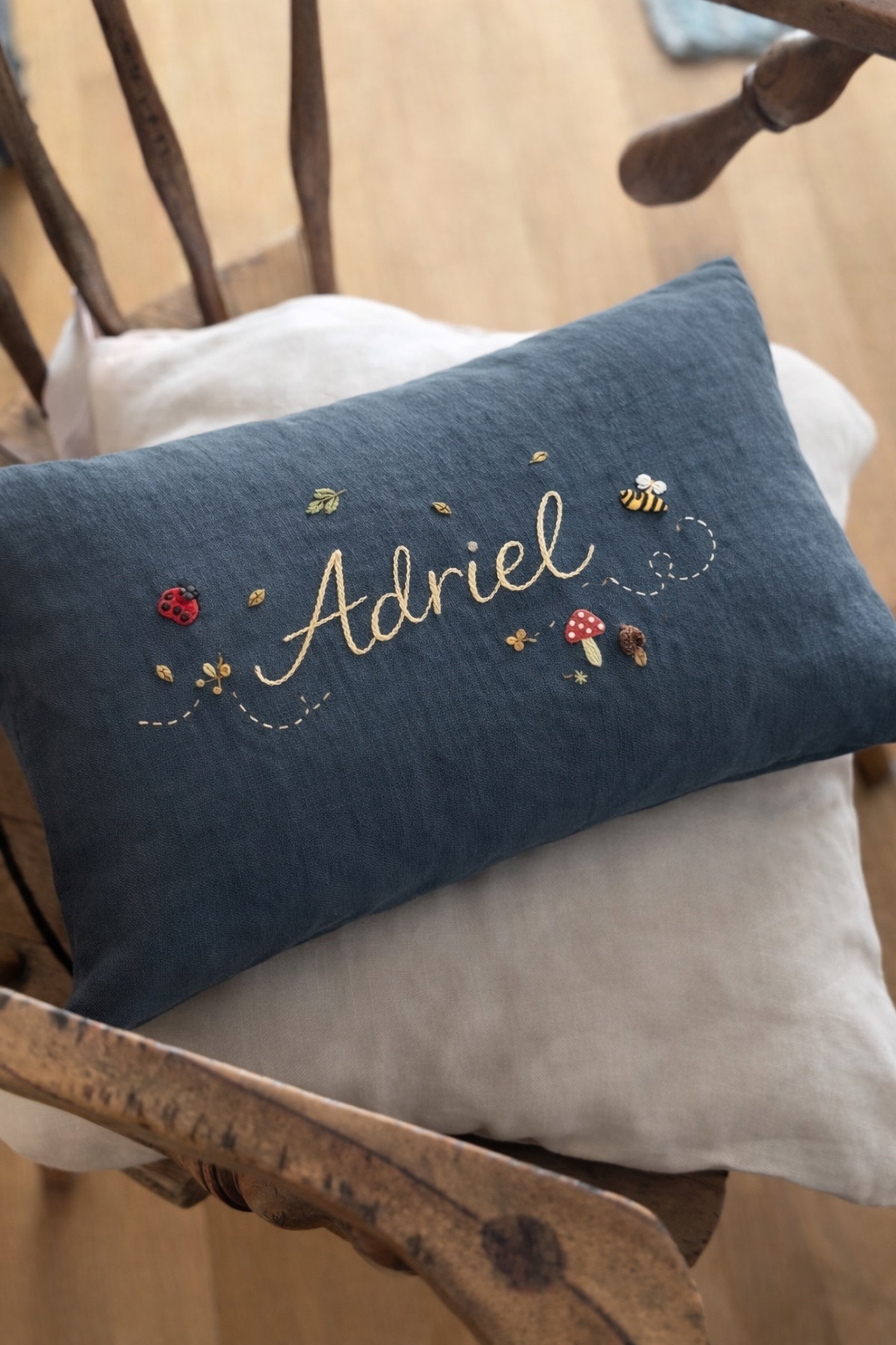 Blue embroidered pillow with name on a wooden chair -  personalised baby / toddler gift.
