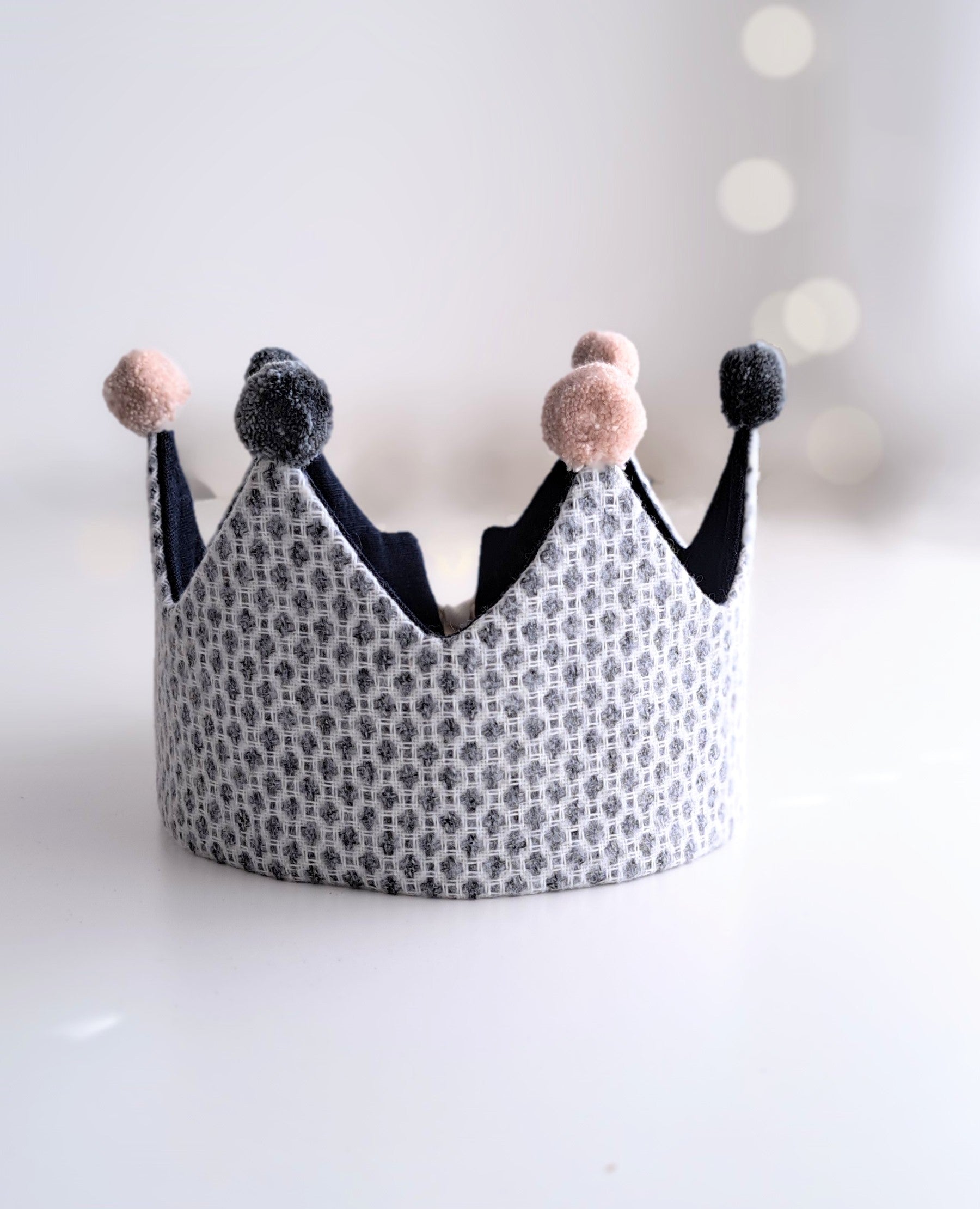Children's crown with pom-pom details on a white background.