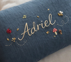 Embroidered name on a blue fabric with decorative elements - personalised baby / toddler gift.