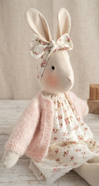 Stuffed bunny toy with a pink floral dress and bow on a wooden surface  -  heirloom baby / toddler gift.