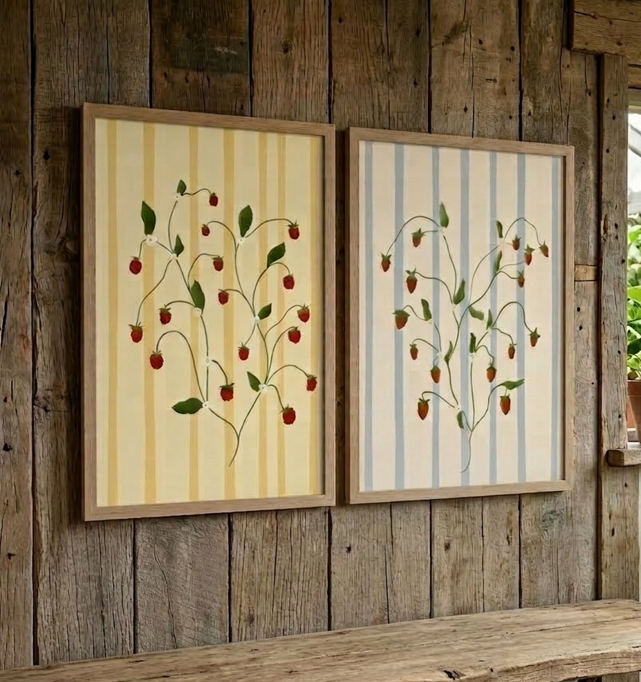 Two framed botanical prints with strawberry designs on a wooden wall.