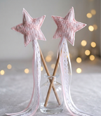 Star-shaped wands with lace detailing in a glass holder against a softly blurred background with lights.