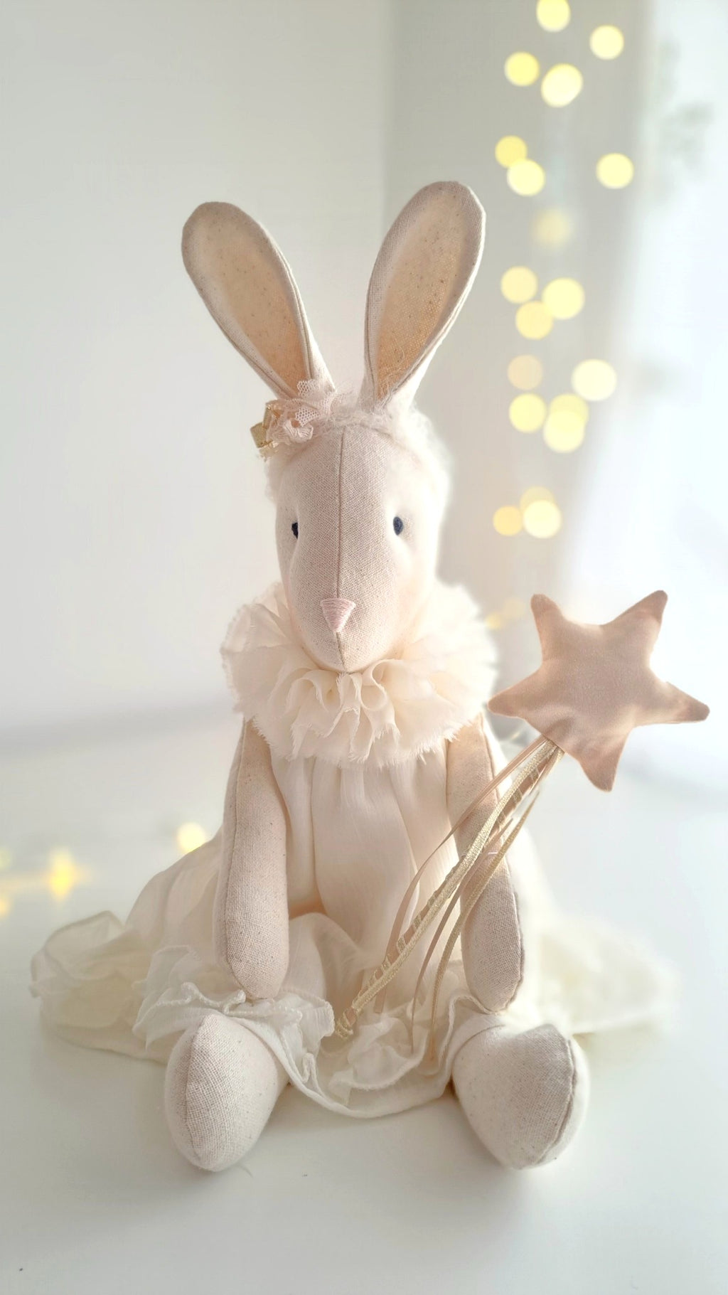 White rabbit plush toy with a star wand on a white background with blurred lights - heirloom baby/toddler gifts.