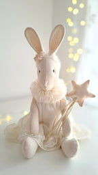 White rabbit plush toy with a star wand on a white background with blurred lights - heirloom baby/toddler gifts.