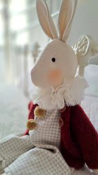 Cute plush rabbit toy with a red outfit and white ruffled collar on a soft surface - heirloom baby/toddler gifts.