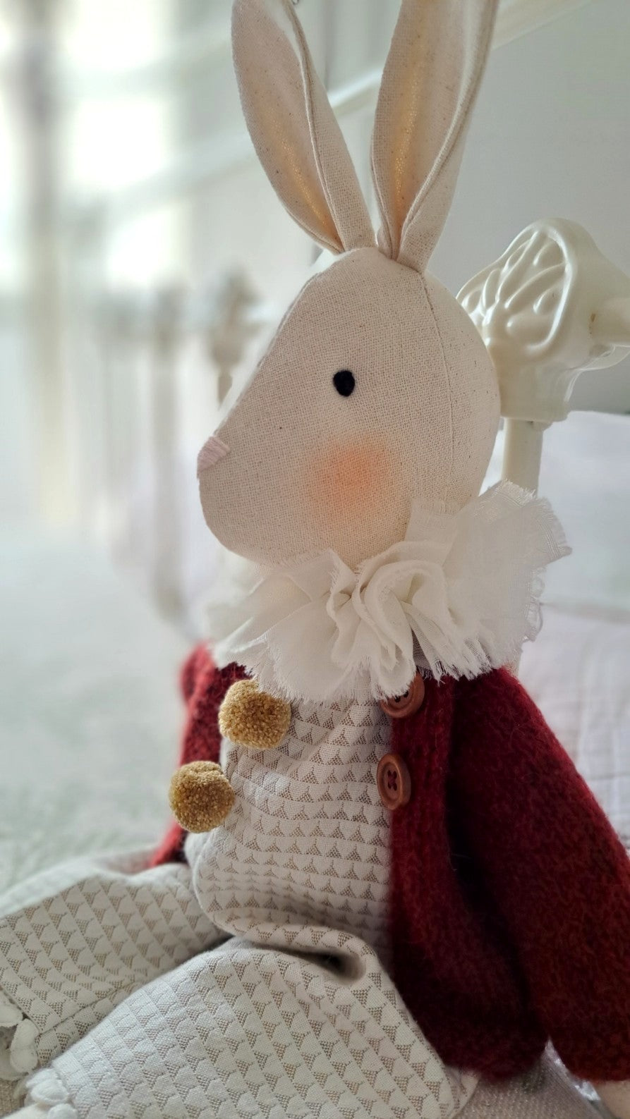 Cute plush rabbit toy with a red outfit and white ruffled collar on a soft surface - heirloom baby/toddler gifts.