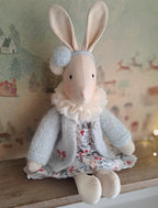 Stuffed rabbit toy with a floral dress and grey coat on a wooden surface- heirloom baby/toddler gifts.